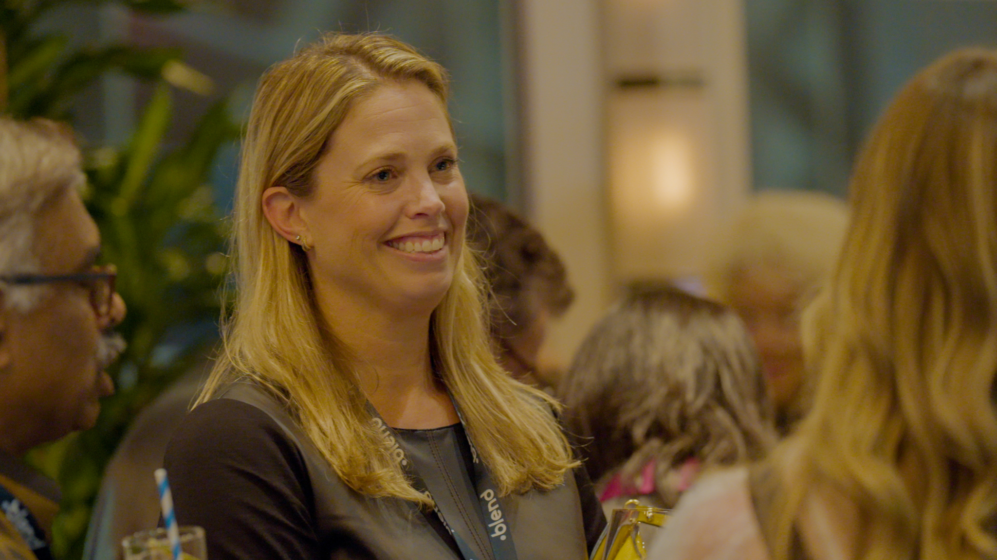 A C-suite professional enjoys conversation at a Blend community networking event. She wears a Blend branded lanyard.